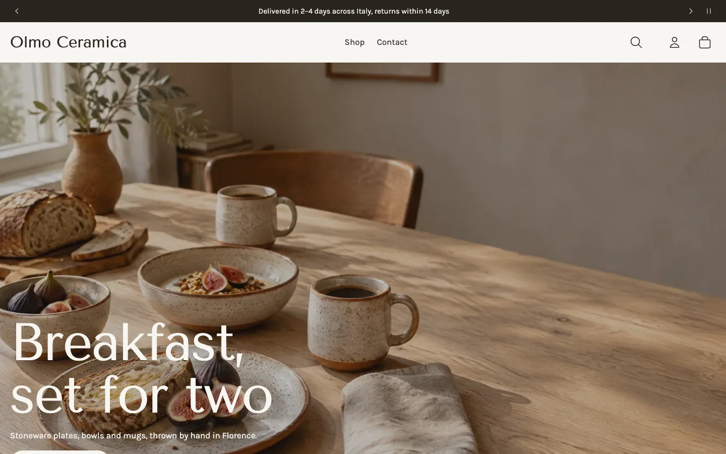 Olmo Ceramica's home page: a full-width photo of a breakfast table set with speckled stoneware, under the heading 'Breakfast, set for two', with the header, menu and an announcement bar above.